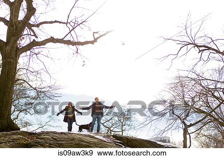 Stock Photo - Young couple and dog standing rock in Central Park, New York, USA. Fotosearch