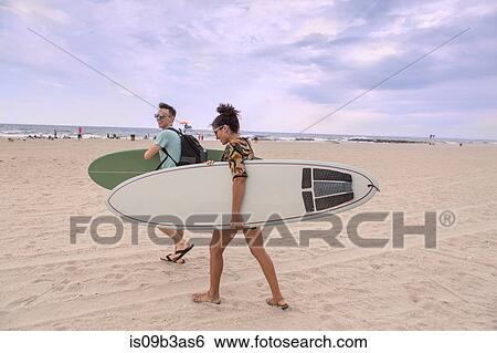 Young couple carrying surfboards on Rockaway Beach, New York State, USA View Large Photo Image Stock Photograph - Young couple carrying surfboards on Rockaway Beach, New York State, USA. Fotosearch