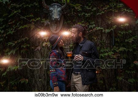 Stock Photo - Young couple chatting in beer garden in evening, Brooklyn, New York, USA. Fotosearch
