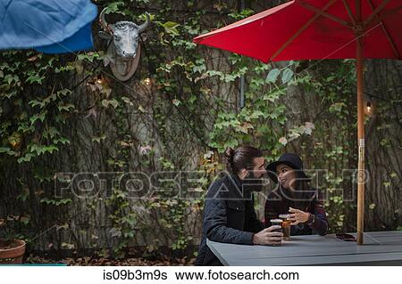 Young couple chatting in beer garden in evening, Brooklyn, New York, USA View Large Photo Image Stock Photograph - Young couple chatting in beer garden in evening, Brooklyn, New York, USA. Fotosearch