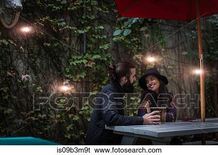 Young couple chatting in beer garden in evening, Brooklyn, New York, USA View Large Photo Image Stock Photograph - Young couple chatting in beer garden in evening, Brooklyn, New York, USA. Fotosearch