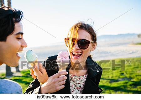 Young couple linking each others arms eating ice cream cones, Venice Beach, California, USA View Large Photo Image Stock Image - Young couple linking each others arms eating ice cream cones, Venice Beach, California, USA. Fotosearch