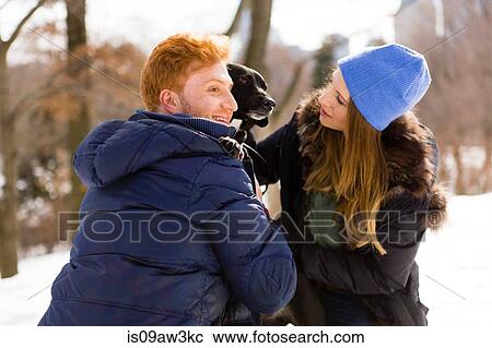 Young couple petting dog in snowy Central Park, New York, USA View Large Photo Image Stock Image - Young couple petting dog in snowy Central Park, New York, USA. Fotosearch
