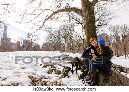 Young couple sitting with dog and drink flask in snowy Central Park, New York, USA View Large Photo Image Stock Image - Young couple sitting with dog and drink flask in snowy Central Park, New York, USA. Fotosearch