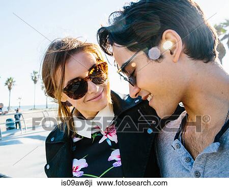 Young couple standing together, outdoors, smiling View Large Photo Image Stock Image - Young couple standing together, outdoors, smiling. Fotosearch