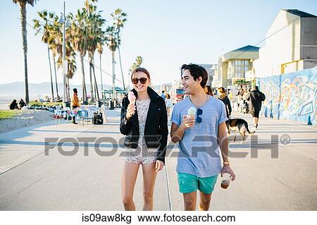 Stock Image - Young couple strolling eating ice cream cones, Venice Beach, California, USA. Fotosearch