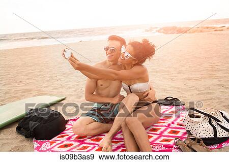 Young couple taking smartphone selfie on Rockaway Beach, New York State, USA View Large Photo Image Stock Photo - Young couple taking smartphone selfie on Rockaway Beach, New York State, USA. Fotosearch