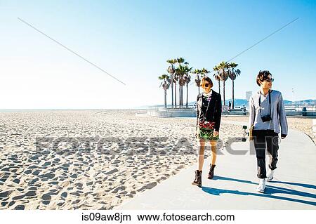 Young couple walking along beach walkway View Large Photo Image Picture - Young couple walking along beach walkway. Fotosearch