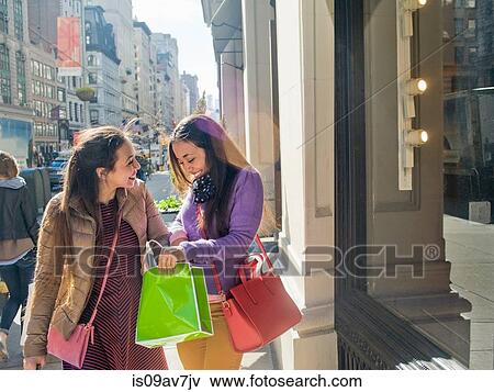 Young female adult twins looking into shopping bags on city sidewalk View Large Photo Image Stock Photo - Young female adult twins looking into shopping bags on city sidewalk. Fotosearch