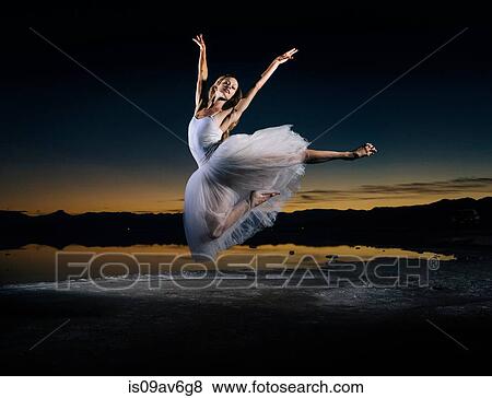 Stock Photo - Young female ballet dancer leaping over Bonneville Salt Flats at sunset, Utah, USA. Fotosearch