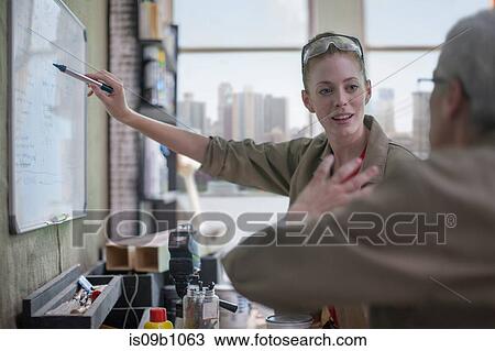 Young female carpenter pointing at whiteboard in furniture making workshop View Large Photo Image Stock Image - Young female carpenter pointing at whiteboard in furniture making workshop. Fotosearch