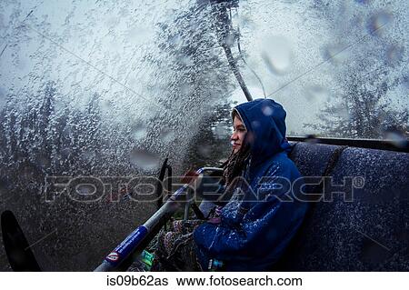 Stock Photograph - Young female hiker in chairlift during mountain snowstorm. Fotosearch