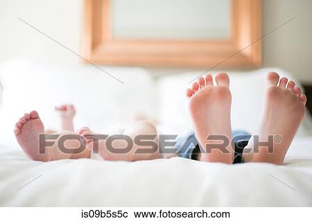 Young girl and baby brother lying on bed, focus on feet View Large Photo Image Stock Image - Young girl and baby brother lying on bed, focus on feet. Fotosearch