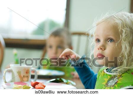 Stock Photograph - Young girl having lunch at table with young boy. Fotosearch