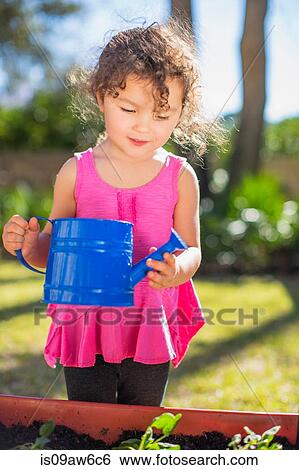 Young girl in garden, holding watering can View Large Photo Image Stock Photograph - Young girl in garden, holding watering can. Fotosearch