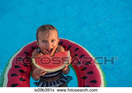Young girl in swimming pool, relaxing on inflatable ring, eating watermelon View Large Photo Image Stock Photograph - Young girl in swimming pool, relaxing on inflatable ring, eating watermelon. Fotosearch