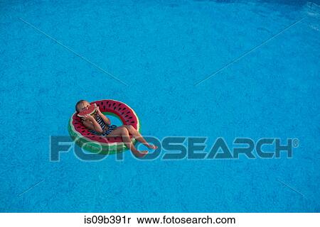 Young girl in swimming pool, relaxing on inflatable ring, eating watermelon View Large Photo Image Stock Photography - Young girl in swimming pool, relaxing on inflatable ring, eating watermelon. Fotosearch