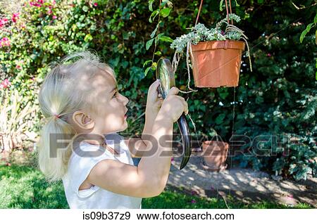 Stock Photo - Young girl looking at plants through magnifying glass. Fotosearch