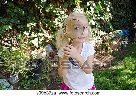 Stock Image - Young girl looking through magnifying glass. Fotosearch