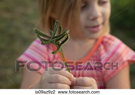 Stock Image - Young girl, outdoors, holding plant. Fotosearch