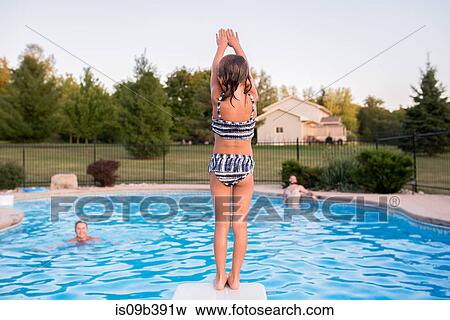 Young girl preparing to dive into swimming pool, father and grandmother watching View Large Photo Image Stock Photo - Young girl preparing to dive into swimming pool, father and grandmother watching. Fotosearch