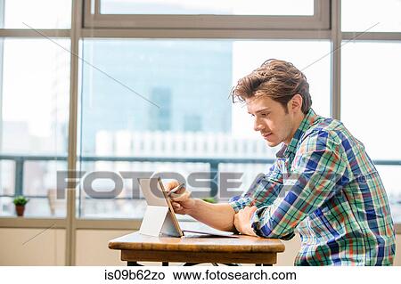 Young male digital designer at office table using laptop View Large Photo Image Picture - Young male digital designer at office table using laptop. Fotosearch