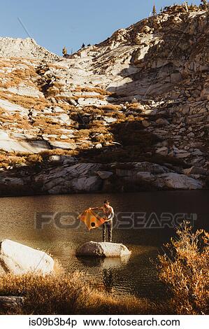Stock Photography - Young male hiker standing on rock in lake with towel, Mineral King, Sequoia National Park, California, USA. Fotosearch