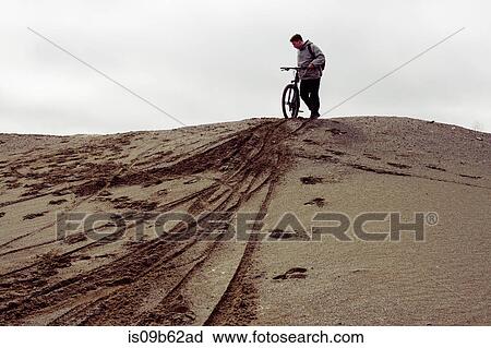 Stock Image - Young male mountain biker preparing to bike from quarry hill. Fotosearch
