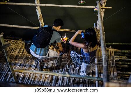 Young man and woman by Ping River in Chiang Mai during Loy Krathong Lantern Festival, releasing floating lantern down the Ping River, Chiang Mai, Thailand View Large Photo Image Stock Photograph - Young man and woman by Ping River in Chiang Mai during Loy Krathong Lantern Festival, releasing floating lantern down the Ping River, Chiang Mai, Thailand. Fotosearch