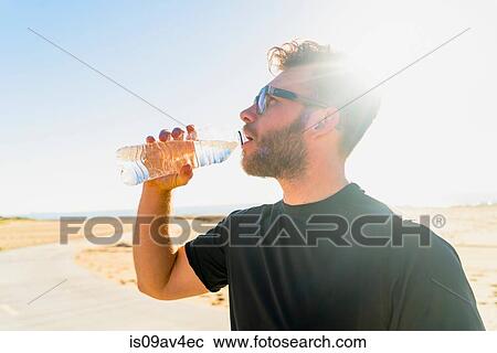 Young man, by beach, drinking from water bottle View Large Photo Image Stock Image - Young man, by beach, drinking from water bottle. Fotosearch