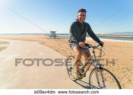 Young man cycling along pathway at beach View Large Photo Image Picture - Young man cycling along pathway at beach. Fotosearch