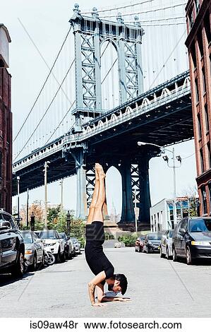 Young man doing yoga handstand in front of Manhattan Bridge, New York, USA View Large Photo Image Stock Photography - Young man doing yoga handstand in front of Manhattan Bridge, New York, USA. Fotosearch