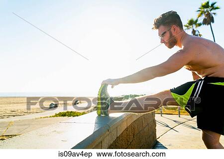 Young man exercising, stretching, outdoors View Large Photo Image Stock Photography - Young man exercising, stretching, outdoors. Fotosearch