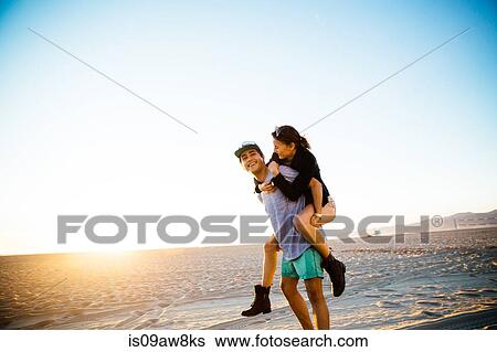 Young man giving girlfriend a piggy back at beach, Venice Beach, California, USA View Large Photo Image Stock Photograph - Young man giving girlfriend a piggy back at beach, Venice Beach, California, USA. Fotosearch
