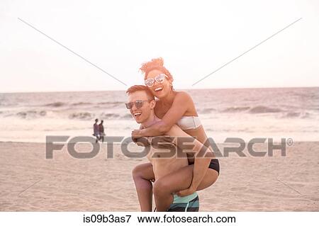 Young man giving piggy back to girlfriend on Rockaway Beach, New York State, USA View Large Photo Image Stock Photo - Young man giving piggy back to girlfriend on Rockaway Beach, New York State, USA. Fotosearch