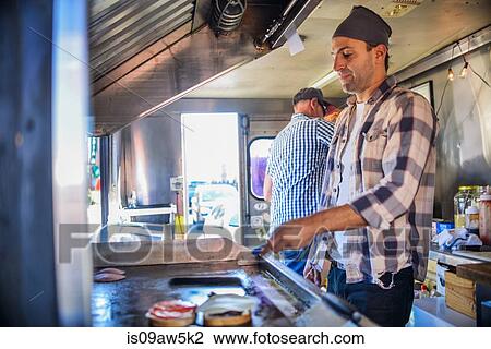 Young man in catering van cooking food on griddle View Large Photo Image Stock Image - Young man in catering van cooking food on griddle. Fotosearch