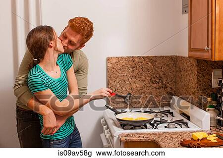 Young man in kitchen arms around young woman cooking on hob, kissing View Large Photo Image Stock Image - Young man in kitchen arms around young woman cooking on hob, kissing. Fotosearch