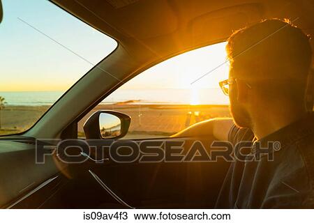Young man looking out of car window at sunset View Large Photo Image Stock Image - Young man looking out of car window at sunset. Fotosearch