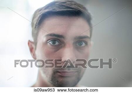 Stock Image - Young man looking through glass, close-up. Fotosearch