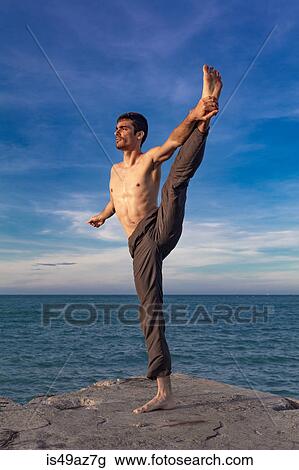Young man outdoors, in yoga position, balancing on one leg View Large Photo Image Stock Image - Young man outdoors, in yoga position, balancing on one leg. Fotosearch