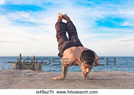 Young man outdoors, in yoga position, balancing on hands View Large Photo Image Stock Image - Young man outdoors, in yoga position, balancing on hands. Fotosearch