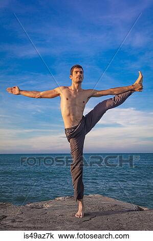 Young man outdoors, in yoga position, balancing on one leg View Large Photo Image Stock Image - Young man outdoors, in yoga position, balancing on one leg. Fotosearch