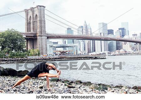 Young man practicing yoga on riverside in front of Brooklyn Bridge, New York, USA View Large Photo Image Stock Image - Young man practicing yoga on riverside in front of Brooklyn Bridge, New York, USA. Fotosearch