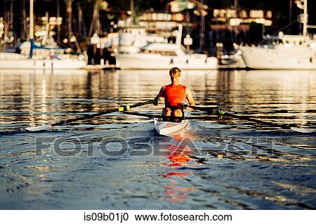 Stock Image - Young man rowing single scull on Puget Sound, Winslow, Bainbridge Island, Washington State, USA. Fotosearch