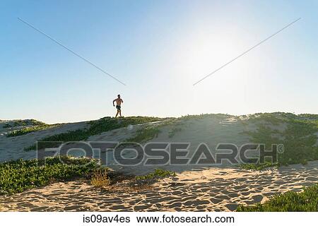 Young man running along sand dunes View Large Photo Image Stock Photograph - Young man running along sand dunes. Fotosearch