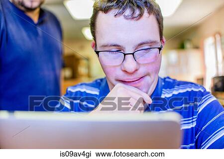 Stock Image - Young man with down syndrome, taking computer training class. Fotosearch