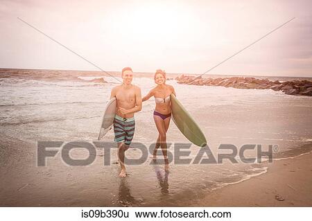 Young surfing couple carrying surfboards on Rockaway Beach, New York State, USA View Large Photo Image Stock Photograph - Young surfing couple carrying surfboards on Rockaway Beach, New York State, USA. Fotosearch