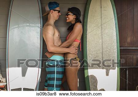 Young surfing couple standing face to face on porch, Rockaway Beach, New York State, USA View Large Photo Image Stock Photo - Young surfing couple standing face to face on porch, Rockaway Beach, New York State, USA. Fotosearch