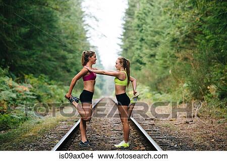 Young woman and teenage girl exercising on rural train track View Large Photo Image Picture - Young woman and teenage girl exercising on rural train track. Fotosearch