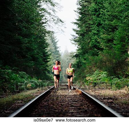 Stock Photo - Young woman and teenage girl running on rural train track. Fotosearch